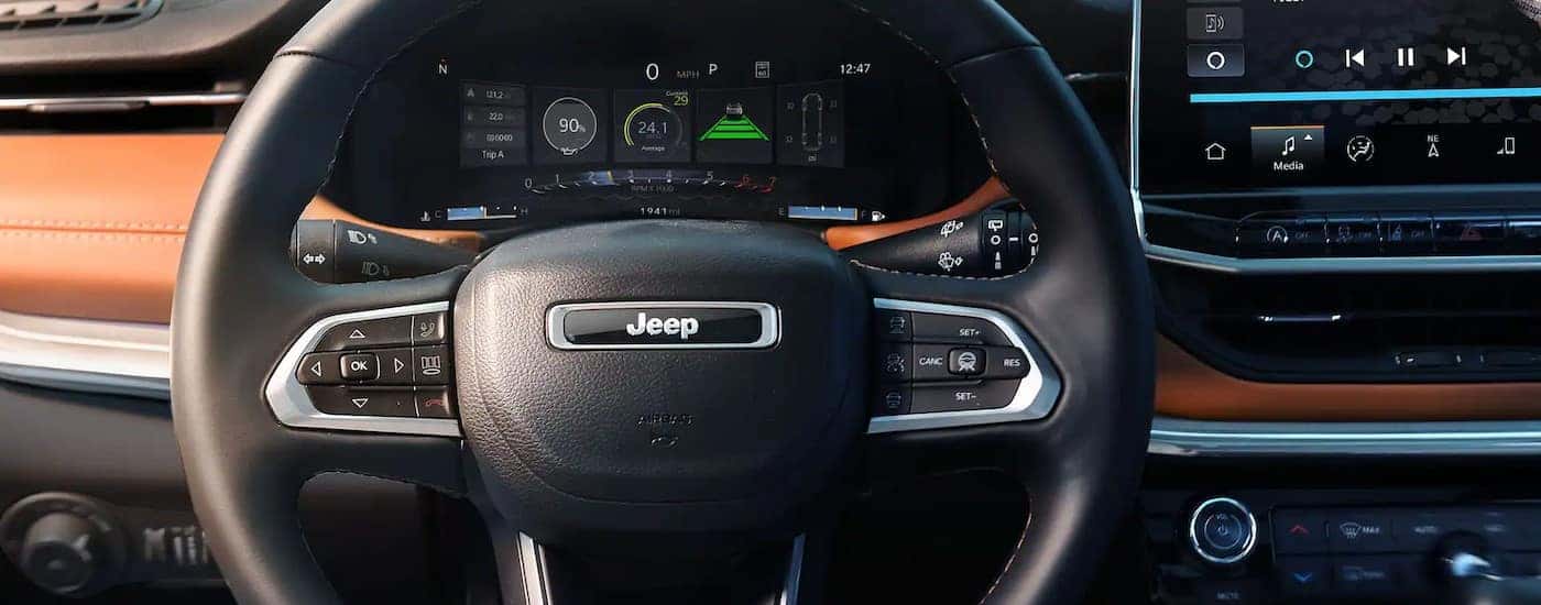A close-up of a steering wheel is shown in a 2025 Jeep Compass.
