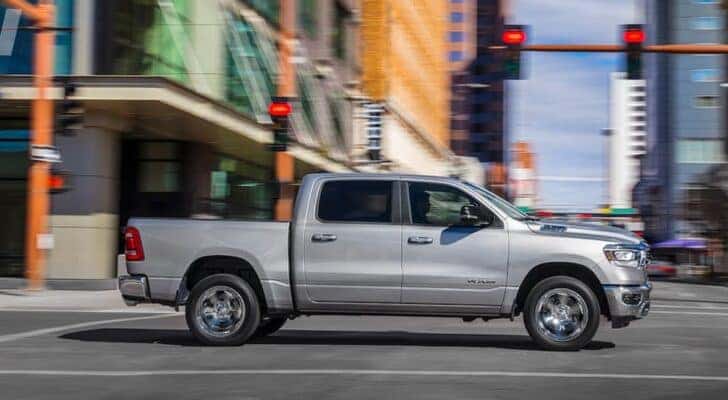 Side angle view of a white 2019 Ram 1500 stopped at an intersection.