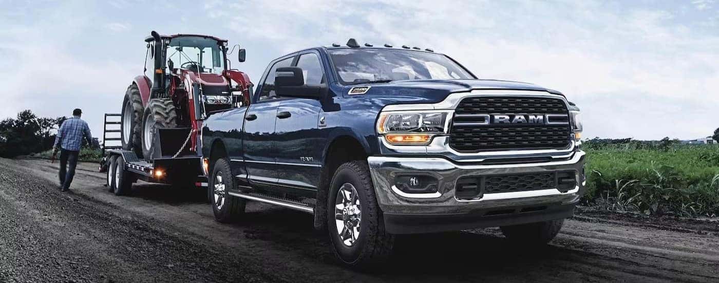 A blue 2024 Ram 2500 Laramie is shown towing a trailer.
