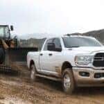 A white 2024 Ram 2500 is shown towing a trailer after viewing used trucks for sale near Covington.