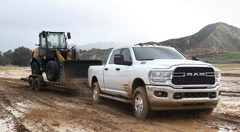 A white 2024 Ram 2500 is shown towing a trailer after viewing used trucks for sale near Covington.