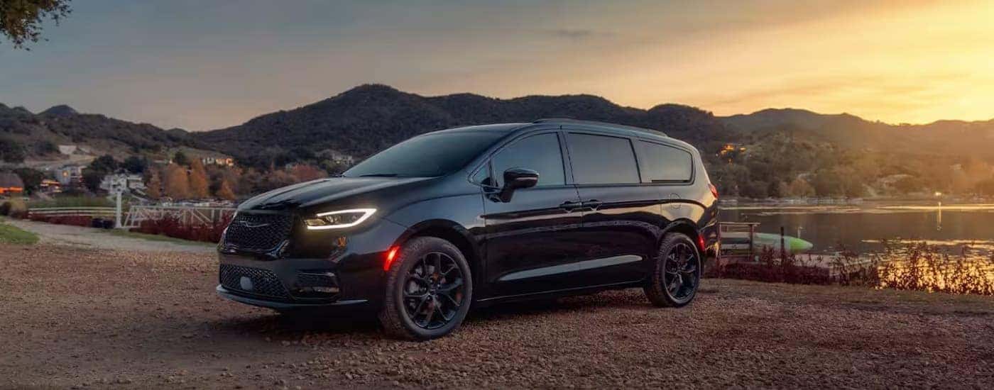 A black 2025 Chrysler Pacifica is shown parked near a lake.