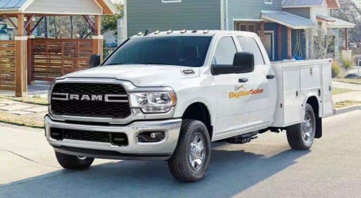 A white 2025 Ram 2500 Chassis Cab is shown parked near a house.