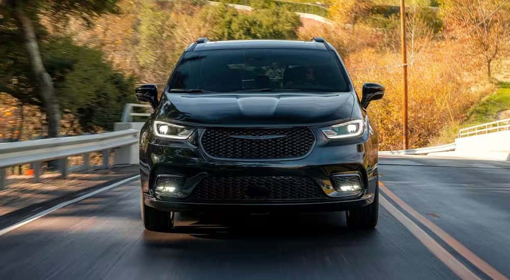 A black 2025 Chrysler Pacifica for sale near Cincinnati is shown driving on a highway.