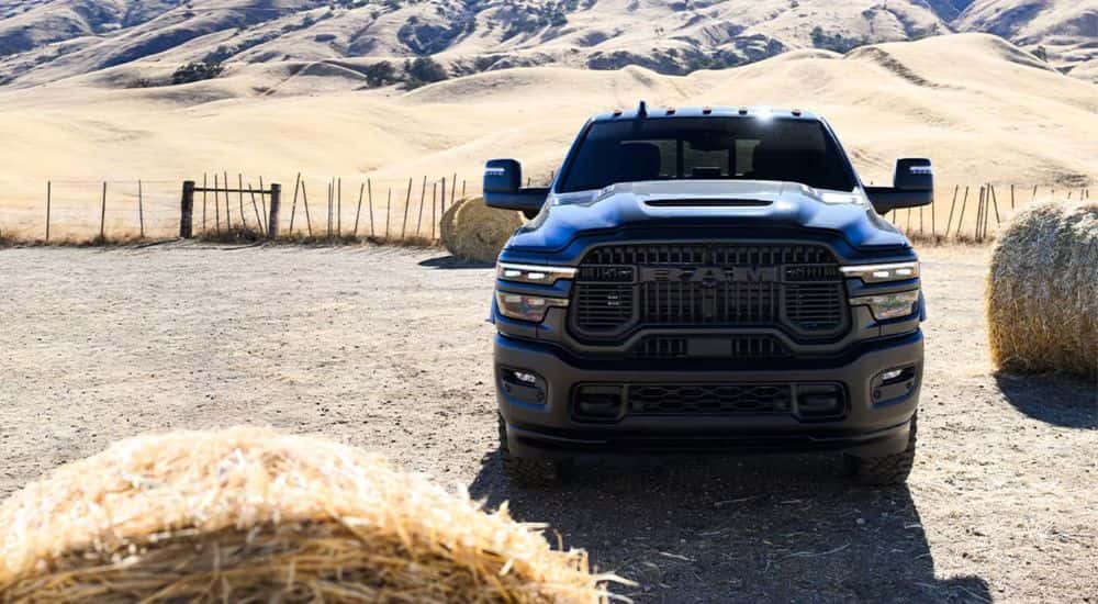 Head-on view of a black 2025 Ram 2500 Rebel parked near bales of hay.