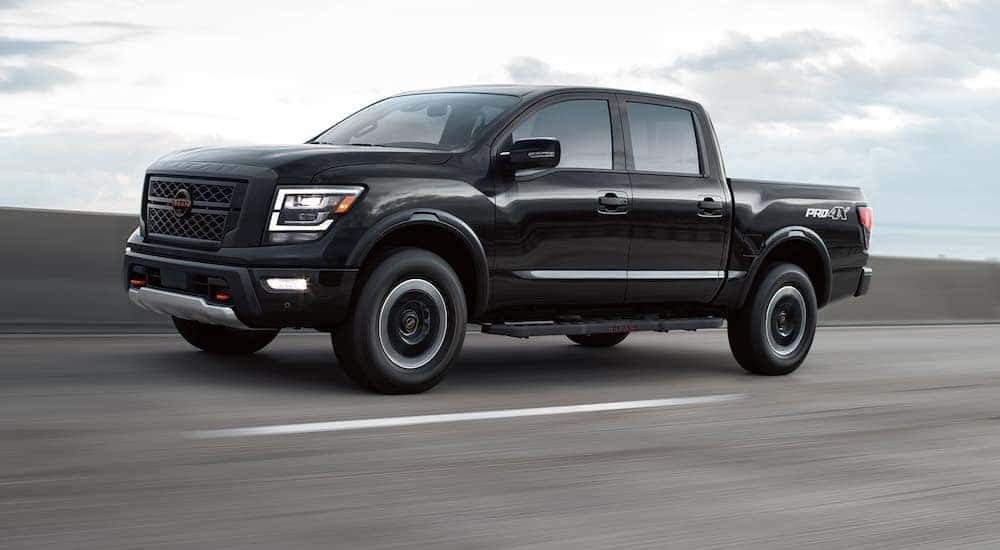 A black 2023 Nissan Titan Pro-4x driving to view used trucks for sale near Burlington.