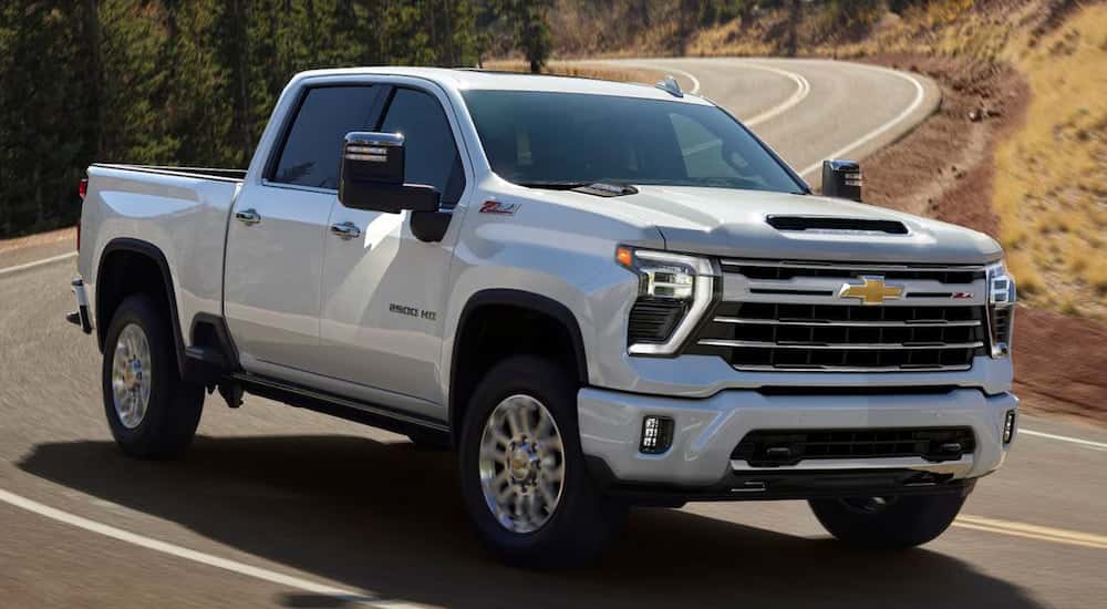 A white 2024 Chevy Silverado 2500 HD driving down a winding road.