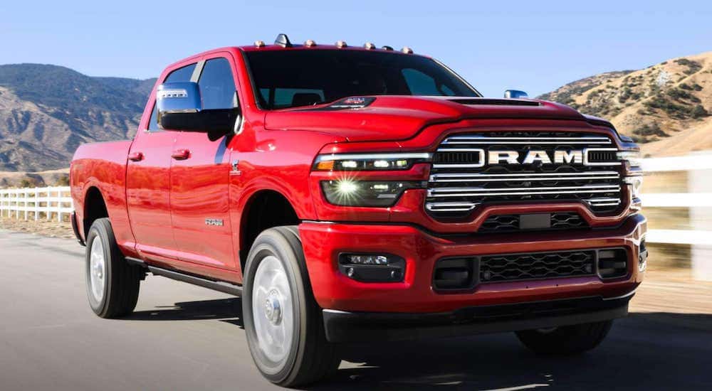A red 2025 Ram 1500 driving on an open road.