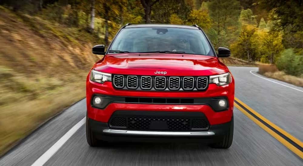 A red 2025 Jeep Compass driving on a highway.