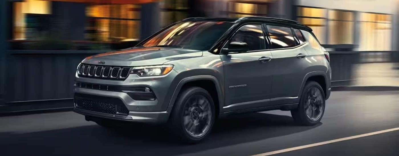 A grey 2023 Jeep Compass for sale near Cincinnati driving through a city.