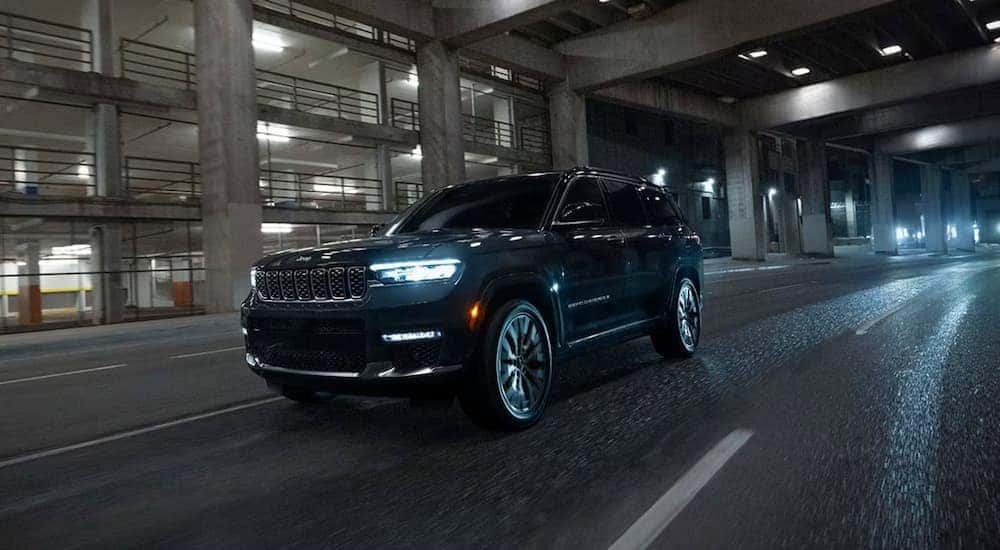 A black 2025 Jeep Grand Cherokee driving down the street at night