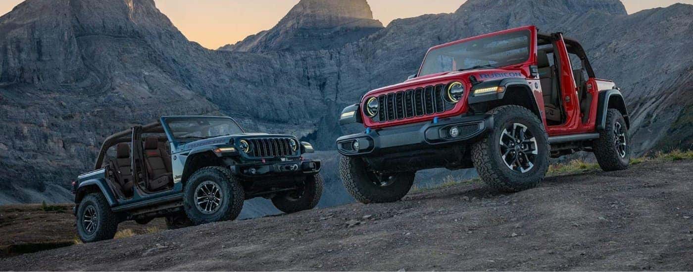 A grey and a red 2025 Jeep Wranglers parked off-road.