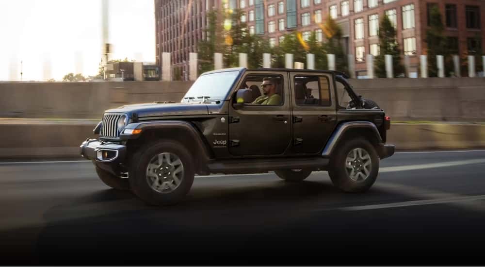 A grey 2025 Jeep Wrangler Unlimited Sahara driving on a city street.