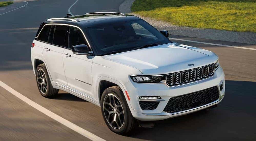 A white 2025 Jeep Grand Cherokee driving on a highway.