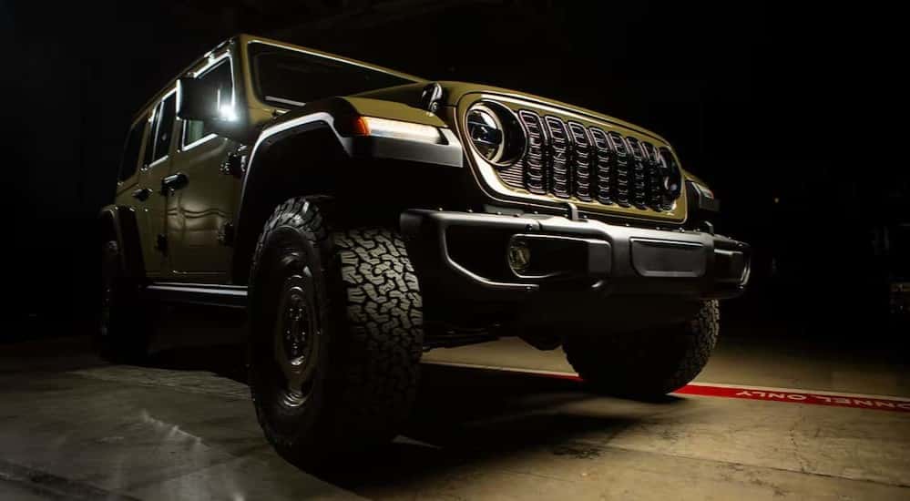 A green 2025 Jeep Wrangler 4xe parked in a dark room.