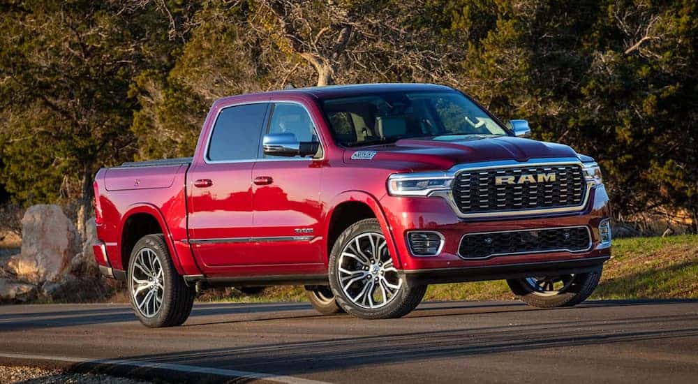 Red 2025 Ram 1500 Tradesman driving down a road.