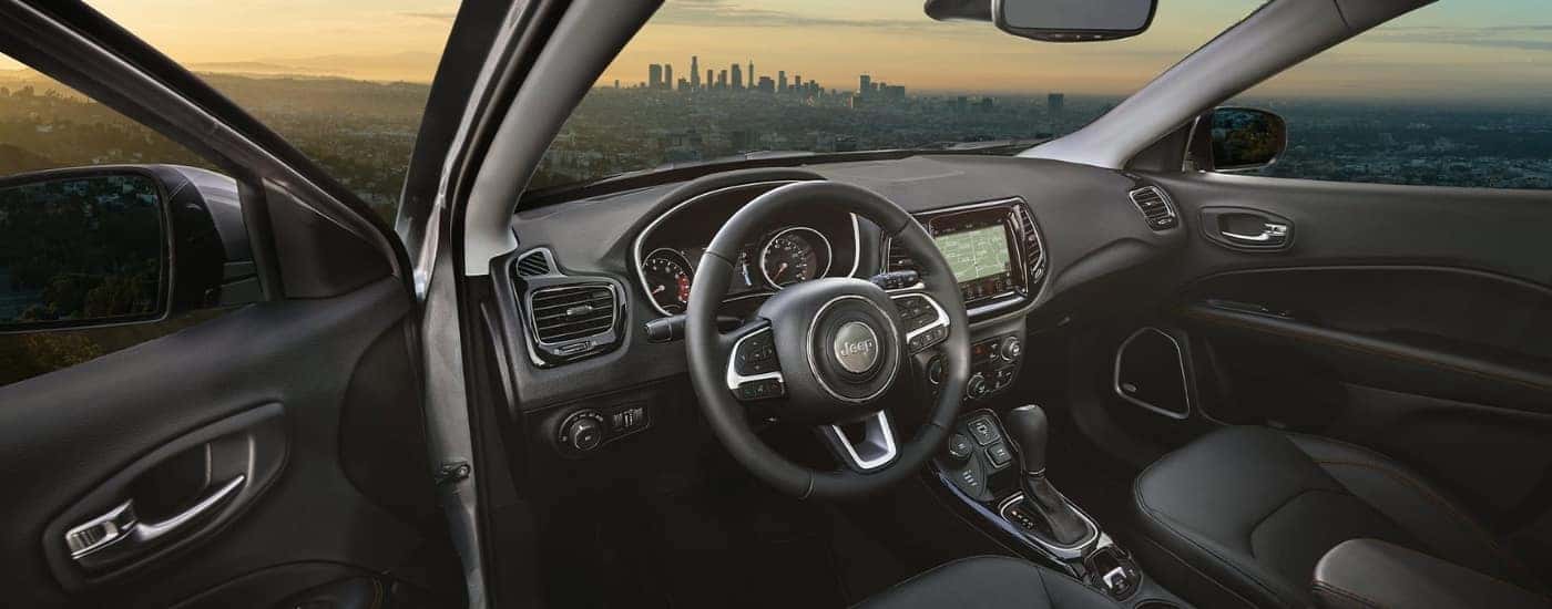 The black interior of a 2021 Jeep Compass with a city in the windshield.