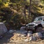 A silver 2024 Jeff Gladiator Rubicon off-roading on rocks