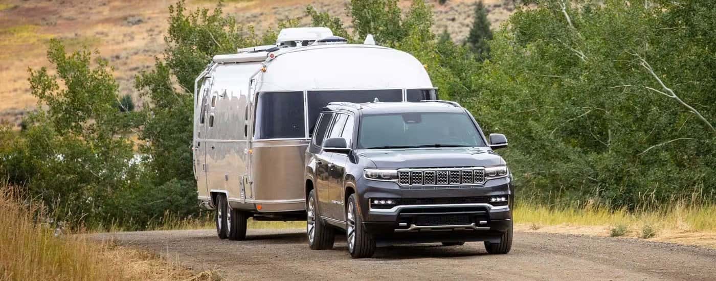 A grey 2025 Jeep Grand Wagoneer towing a trailer.