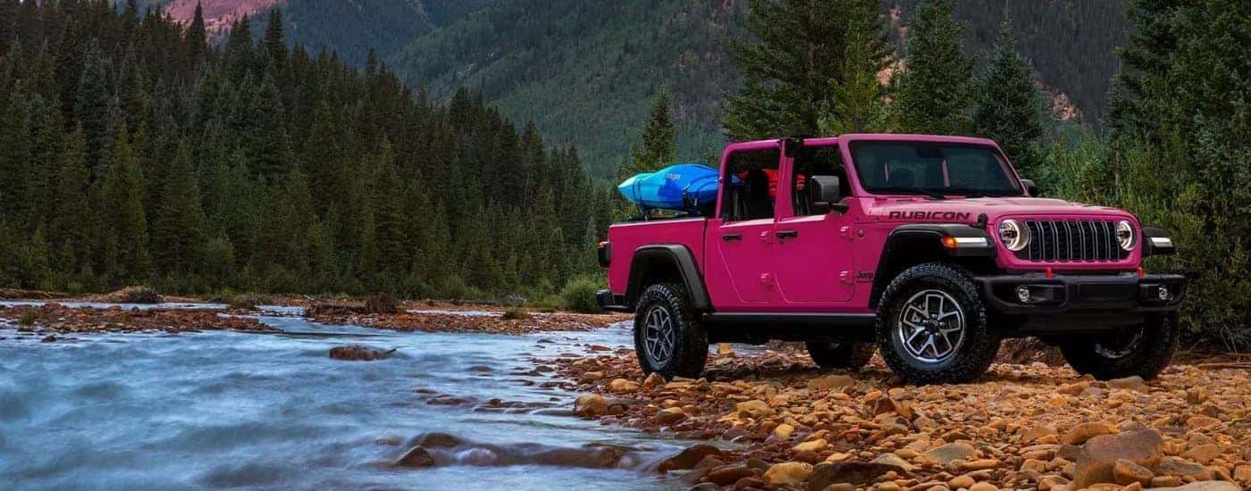 A pink 2024 Jeep Gladiator for sale near Alexandria parked near a river.