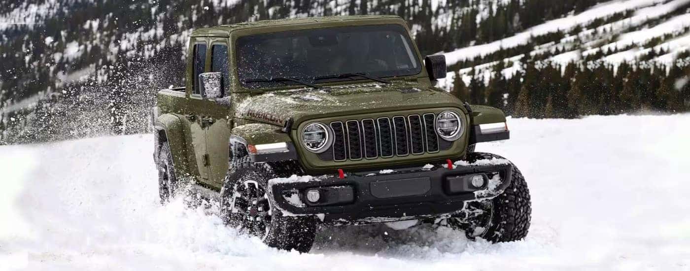 A green 2025 Jeep Gladiator Rubicon off-roading in snow.