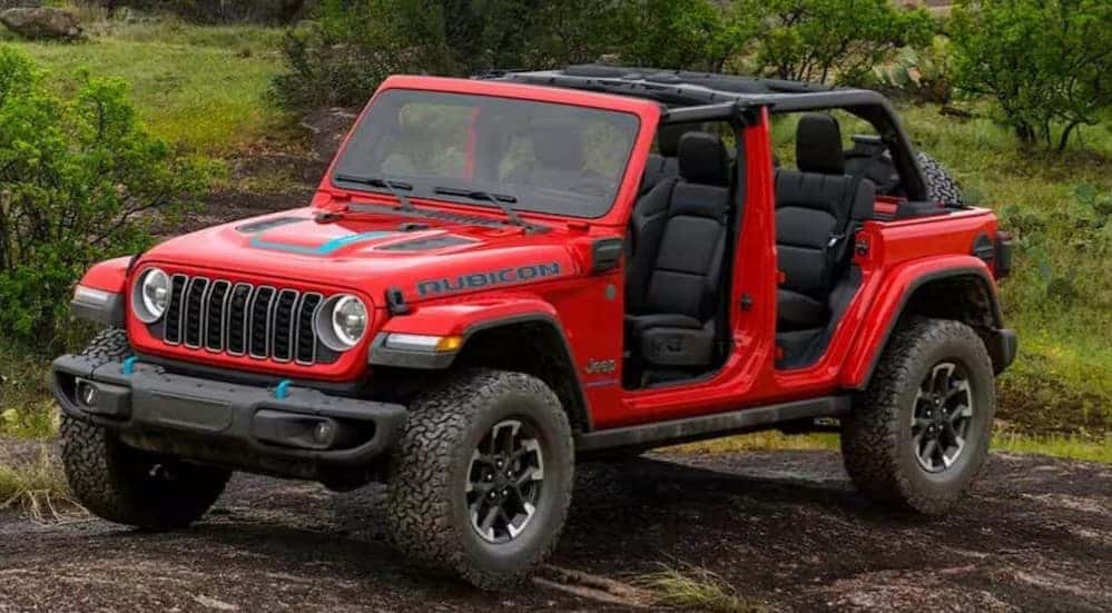 A red 2025 Jeep Wrangler Rubicon 4xe parked off-road.
