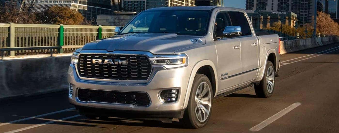 Grey 2025 Ram 1500 Tungsten for sale near Burlington driving down a road.