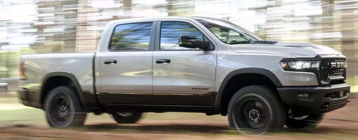 Silver 2025 Ram 1500 driving through a forest.