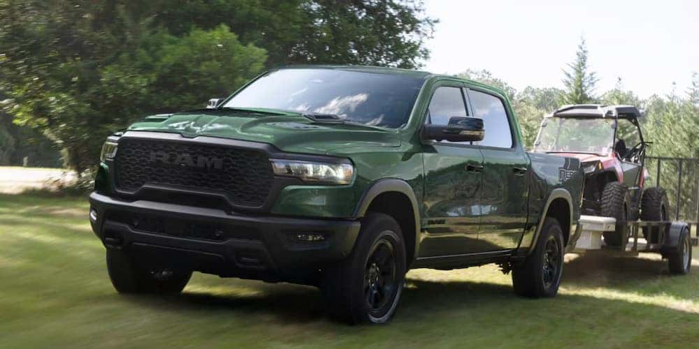 Green 2026 Ram 1500 towing all-terrain-vehicle.