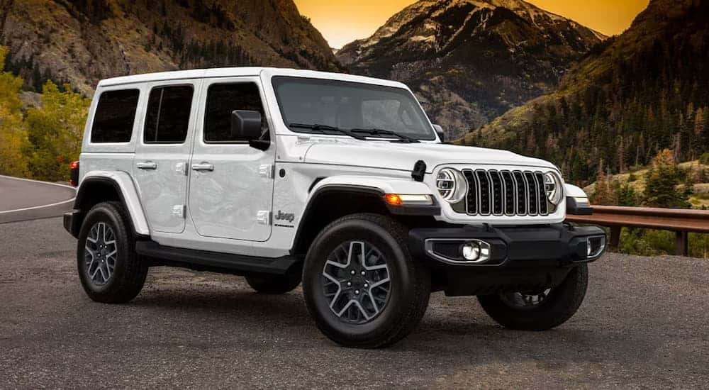 White 2025 Jeep Wrangler from the front at an angle parked in the mountains.