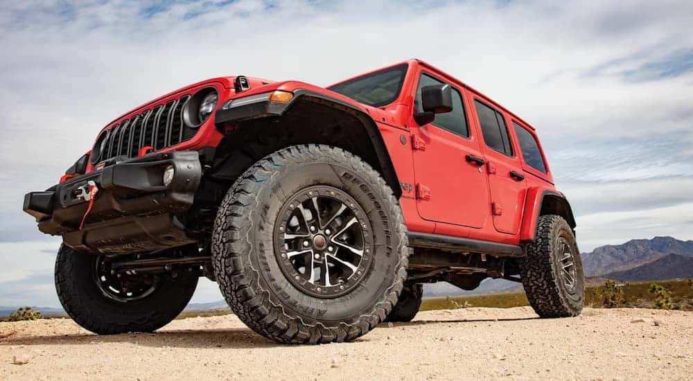 Red 2025 Jeep Wrangler at an angle from below parked in the desert.