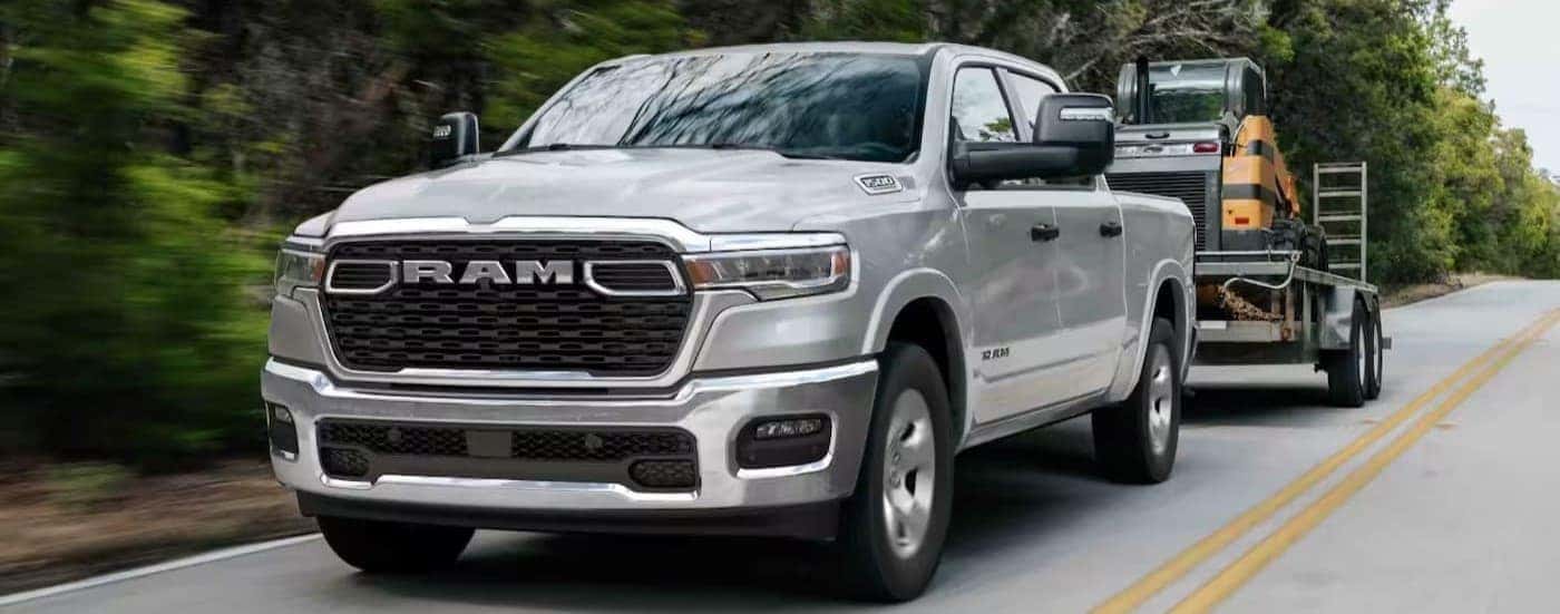 A silver 2026 Ram 1500 Big Horn towing a trailer.