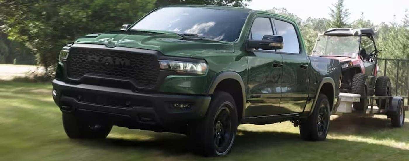 A green 2026 Ram 1500 Rebel towing a trailer.