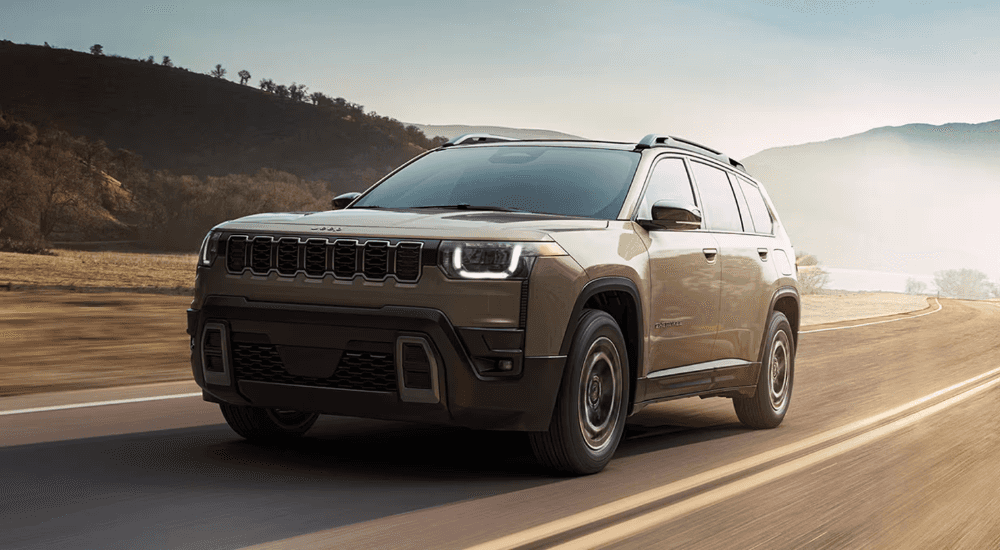 Green 2026 Jeep Cherokee driving down an empty street