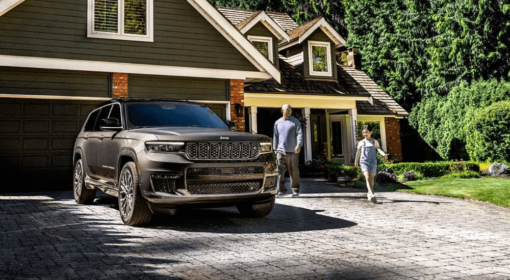 A father and daughter walk up to their 2025 Jeep Grand Cherokee Altitude X