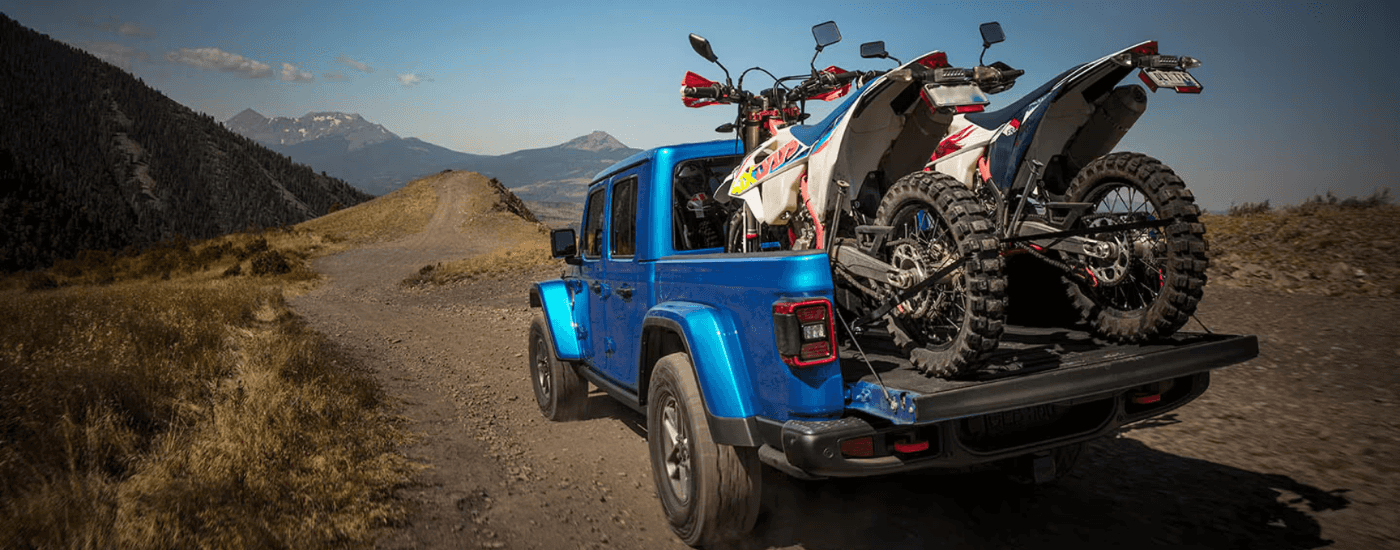 Blue 2025 Jeep Gladiator hauling two dirtbikes