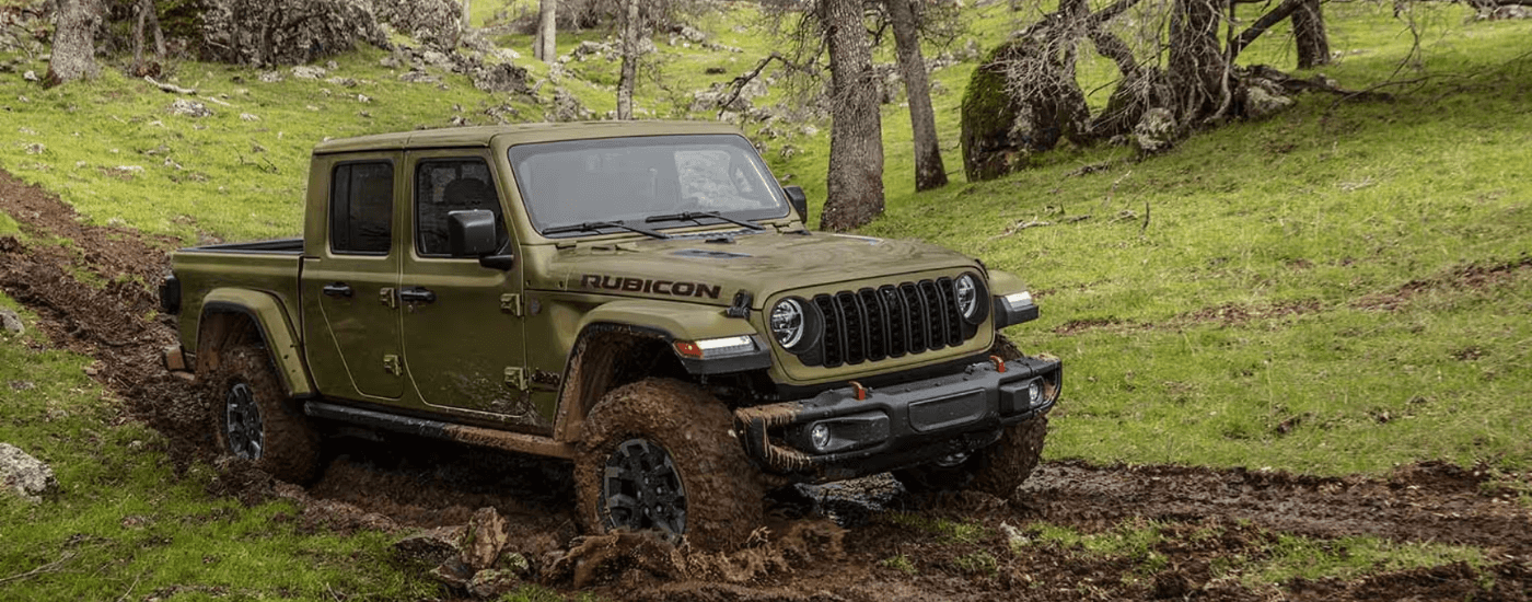 Green 2025 Jeep Gladiator driving through mud off-road
