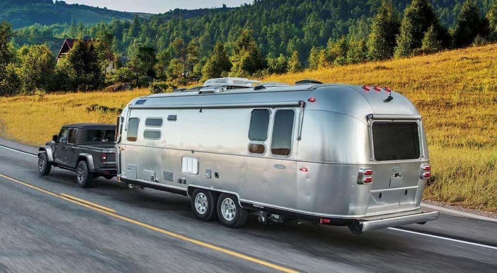 Towing a trailer is a gray 2026 Jeep Gladiator for sale near Independance.