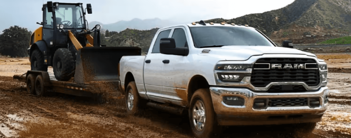 White 2026 Ram 2500 towing a skid steer