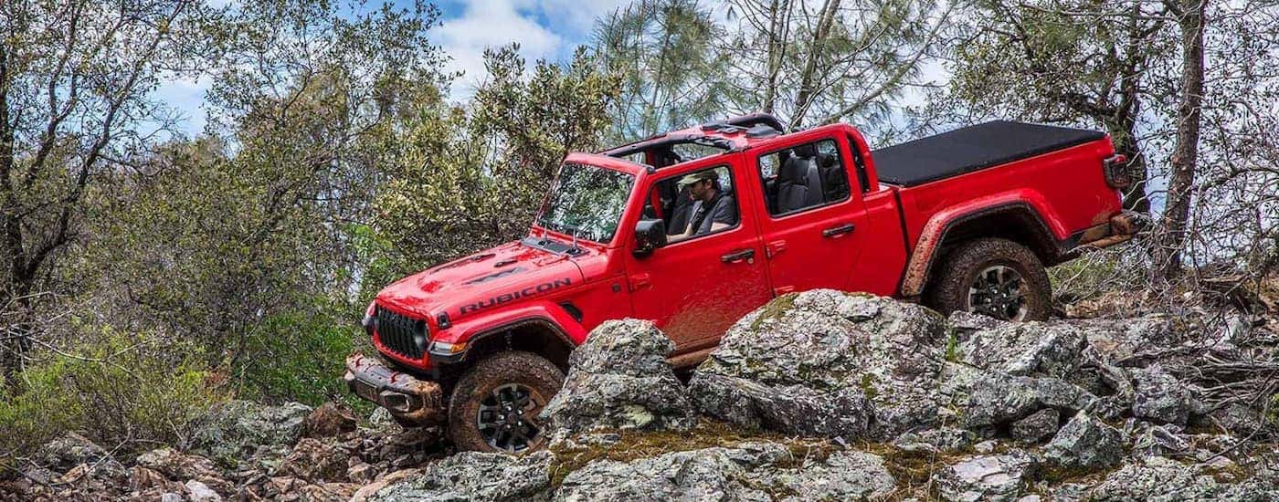 A red 2025 Jeep Gladiator Rubicon off-roading on rocks