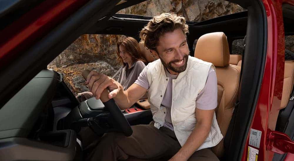Two people driving in a red 2026 Jeep Recon