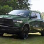 Green 2026 Ram 1500 towing an ATV on a trailer