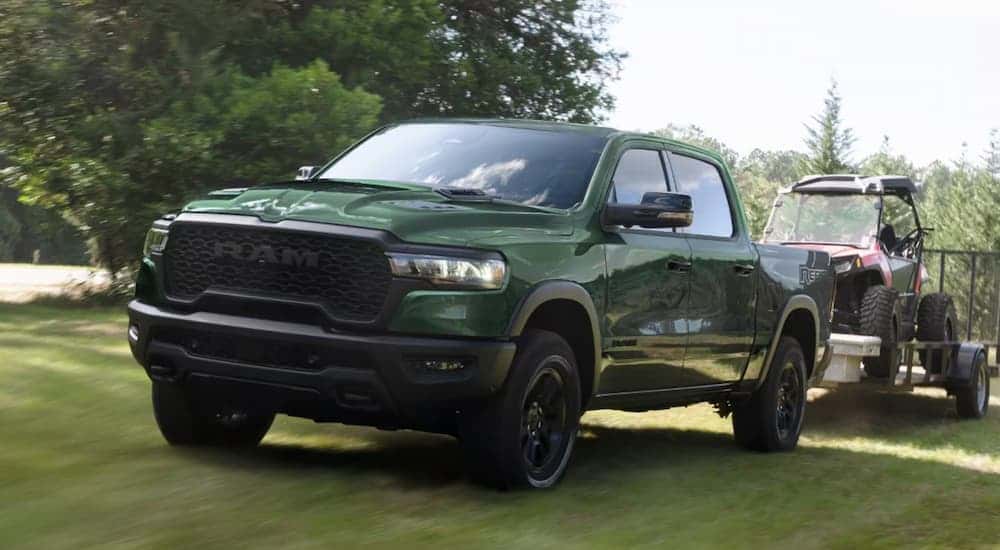 Green 2026 Ram 1500 towing an ATV on a trailer