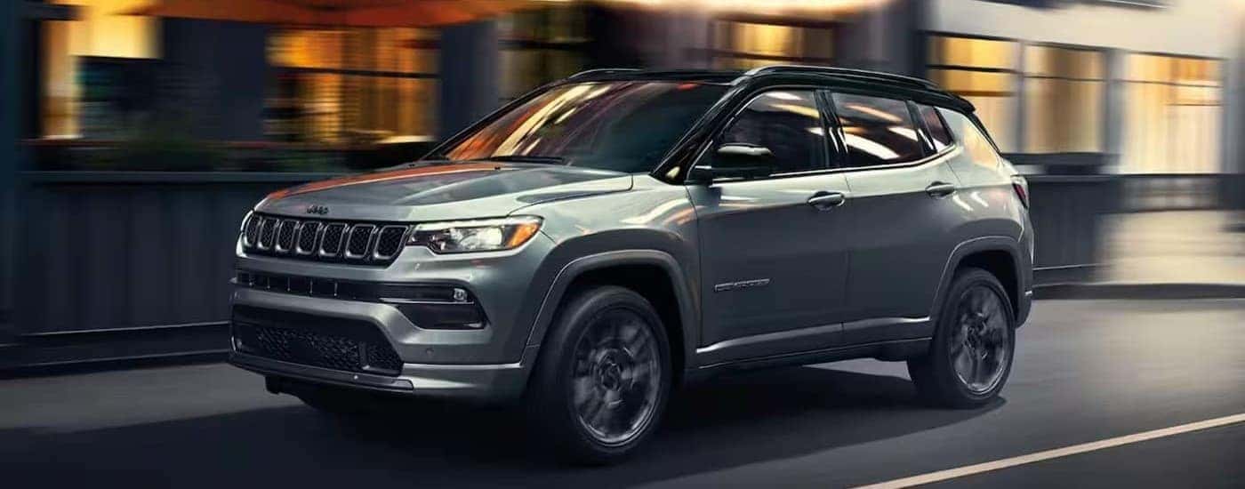 A silver 2023 Jeep Compass driving in a city.
