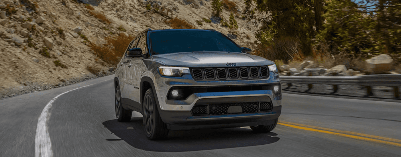 Silver 2026 Jeep Compass driving down an open road
