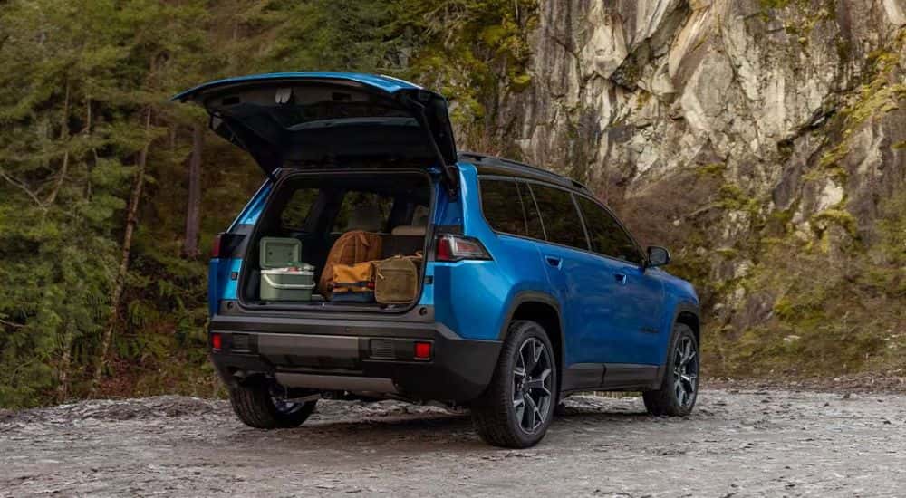 Blue 2026 Jeep Cherokee with an open, loaded trunk parked in a forrest