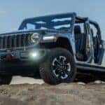 Gray 2026 Jeep Gladiator Rubicon X edition with no doors or roof on a rocky hill