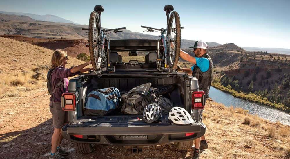 Gray 2026 Jeep Gladiator with a couple loading mountain bikes into the truck bed