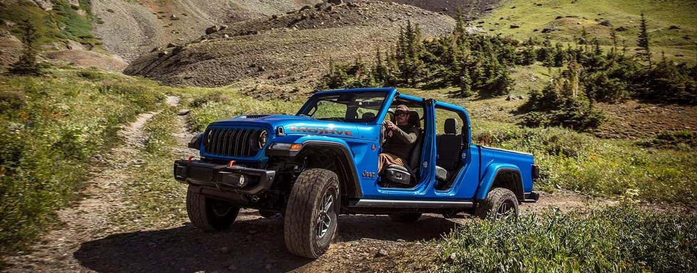 A blue 2026 Jeep Gladiator Mojave off-roading on a trail