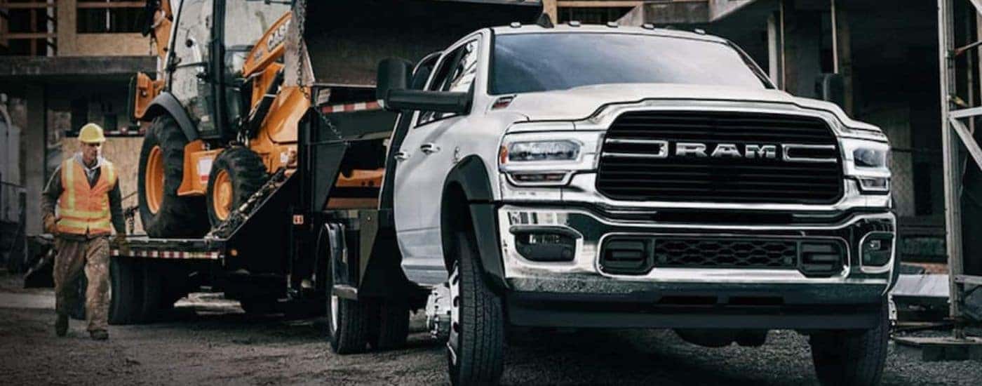 White 2020 Ram Chassis Cab truck towing an excavator